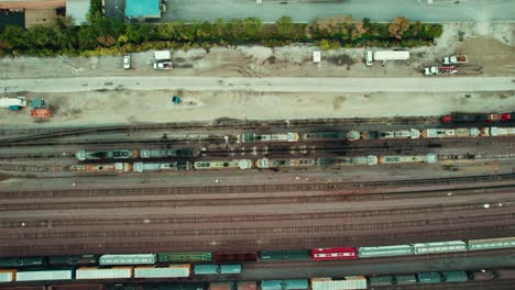 Top-down-aerial-view-of-expansive-railway-systems,-showcasing-cargo-and-commuter-trains,-intricate-track-layouts,-modern-infrastructure,-enhanced-safety-measures