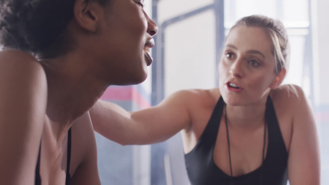 video de una diversa entrenadora de fitness hablando con una mujer agotada después de hacer ejercicio en un gimnasio