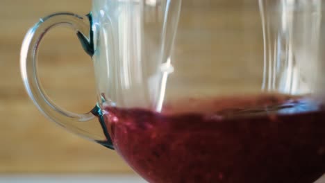 primer plano de una taza de vidrio llena de una bebida rojiza
