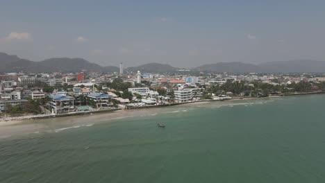 Flyover shallow beach to Hua Hin cityscape skyline in coastal Thailand