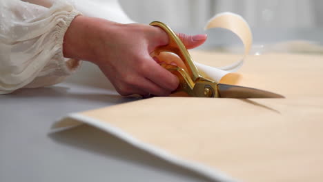 young female designer with tape-line on her neck standing in dressmaking studio and drawing lines with chalk and rule. female couturier in atelier cutting out a pattern for future clothes.