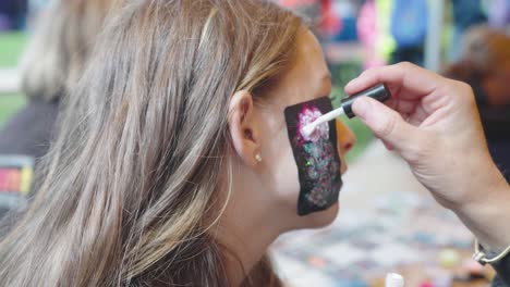 Glitter-temporary-tattoo-of-a-rose-being-painted-on-a-teenage-girl