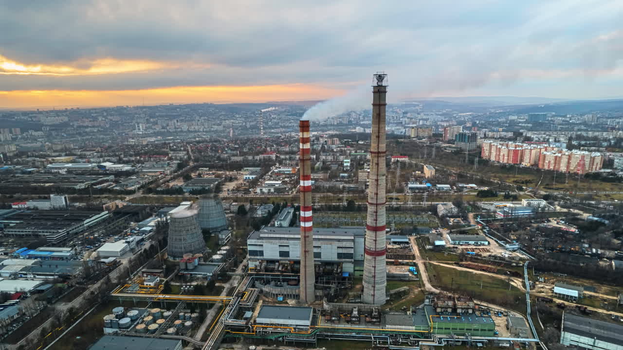 Aerial drone timelapse view of thermal power plant in Chisinau at cloudy weather, Moldova. View of pipes with felling steam, cityscape, sunset