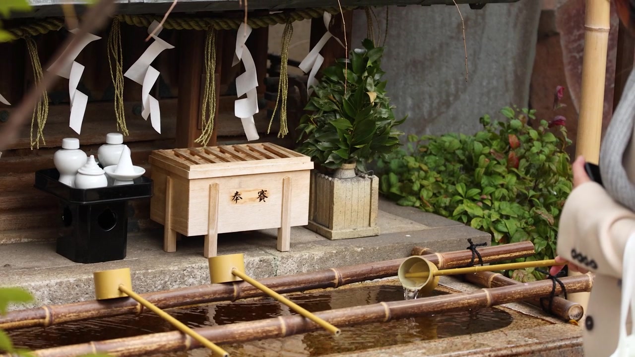 Mulher usa uma concha de bambu para o ritual de purificação das mãos em um santuário em Tóquio, Japão