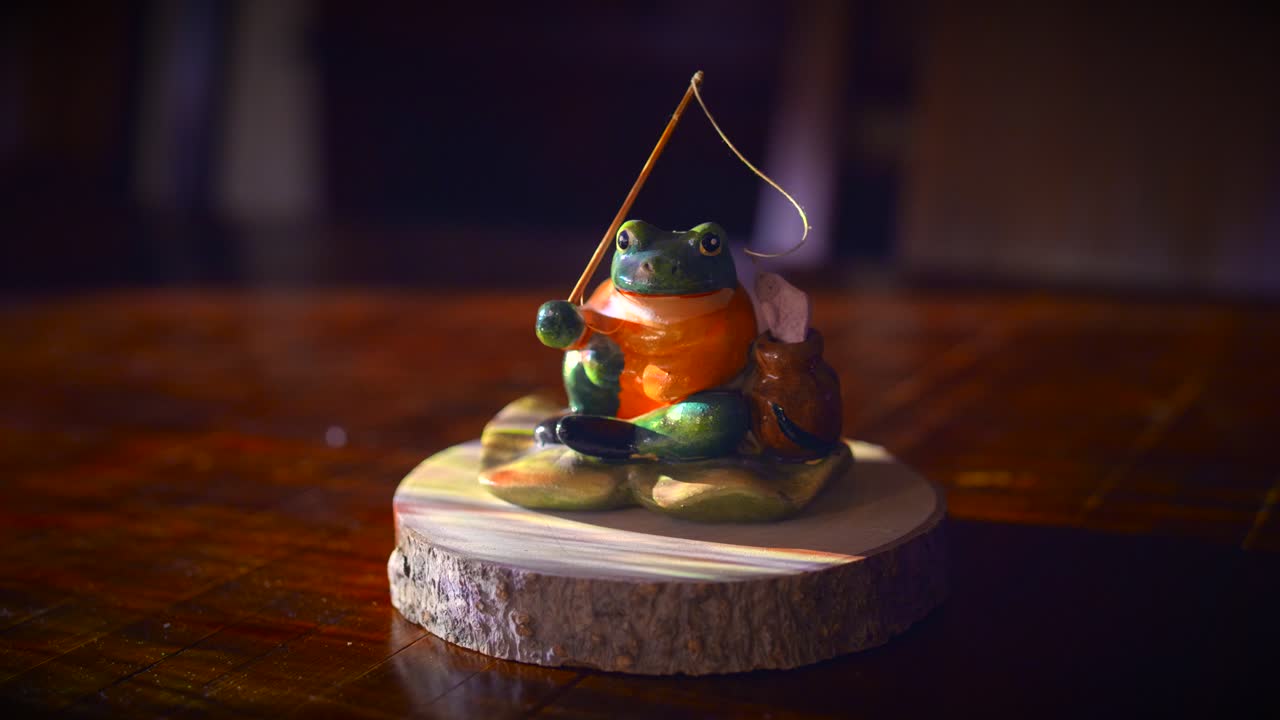 la luz se ilumina en la rana de pesca de cerámica en una pantalla de madera