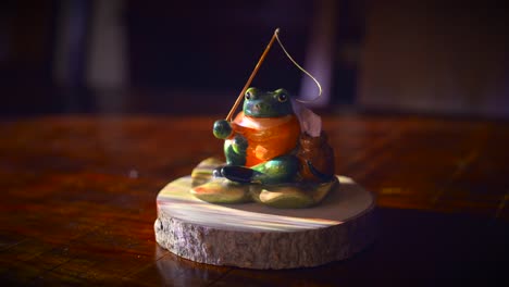 light illuminates on the ceramic fishing frog on a wood display