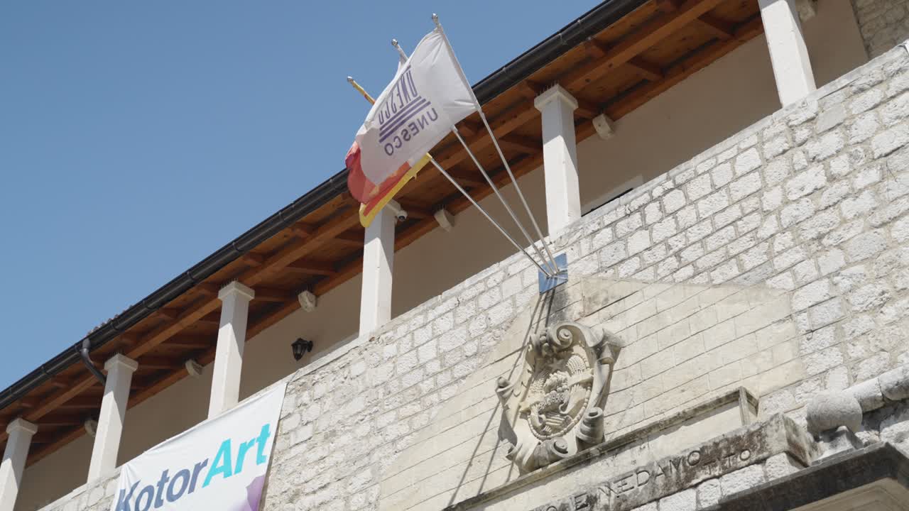 Blazon and Flaggs of Unesco, Kotor and Montenegro over the sea gate entrace of the city walls and old town in Kotor showing details
