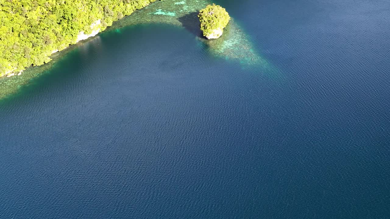 Cảnh quay drone góc cao cho thấy những hòn đảo đá vôi xanh tươi được bao quanh bởi nước biển màu ngọc lam trong vắt.