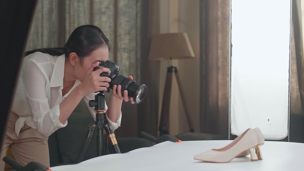 アジアの女性写真家がホームスタジオに入って女性の靴の写真を撮っています