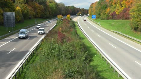 fast driving cars on a freeway, framed by wonderful autumn colored trees - dynamic zoomed-out