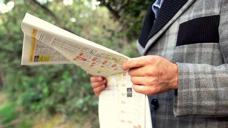 Uomo d'affari che legge il giornale in giardino