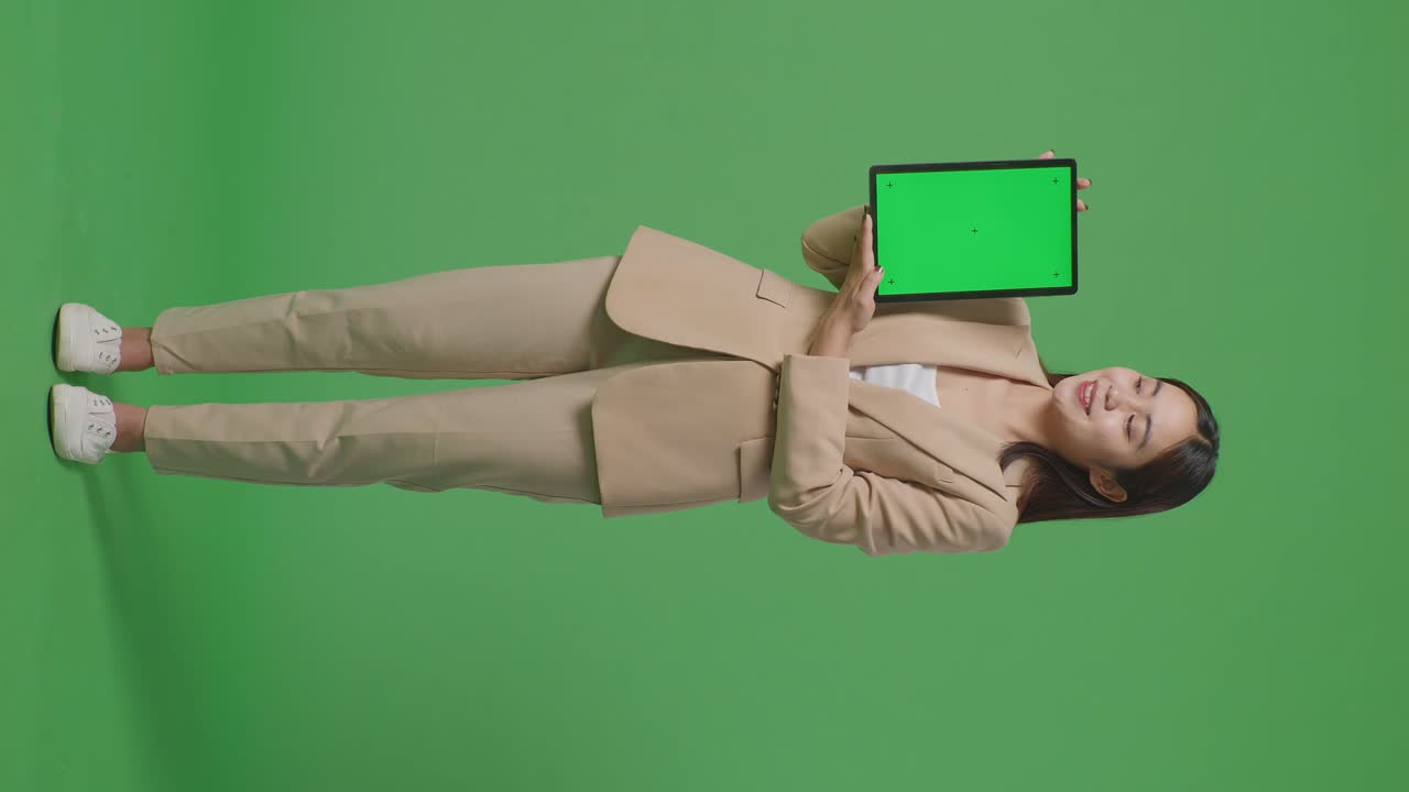 mujer de traje marrón sosteniendo una tableta de pantalla verde