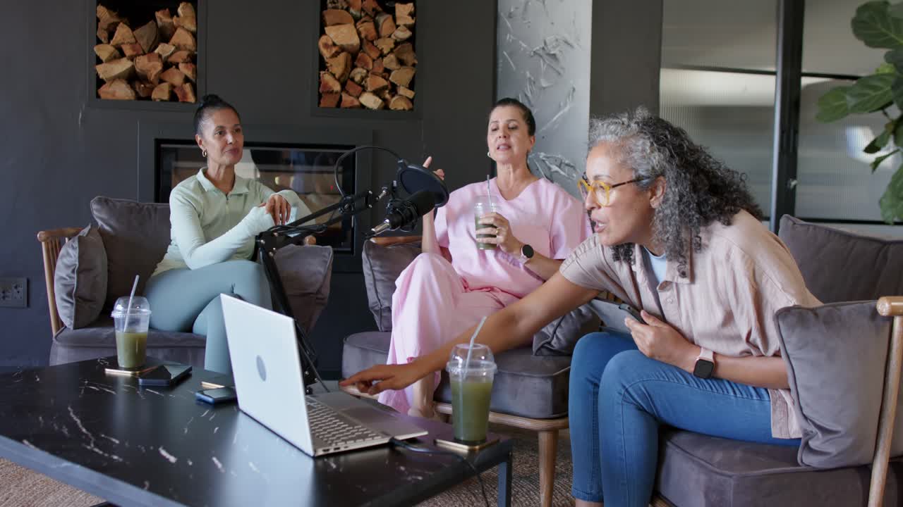 Diverse donne a casa che reagiscono al segnale del laptop per registrare, mentre l'host di destra tocca e sposta il microfono.