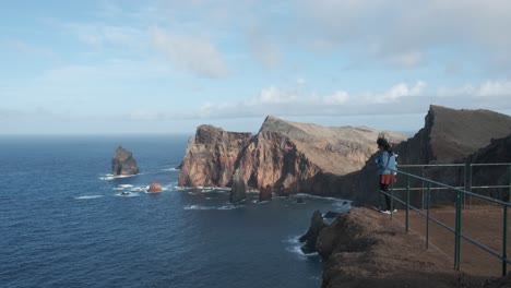 Joven-Asiática-Ondeando-Una-Bufanda-En-El-Viento-Con-El-Hermoso-Paisaje-De-Ponta-De-São-Lorenço-En-El-Fondo