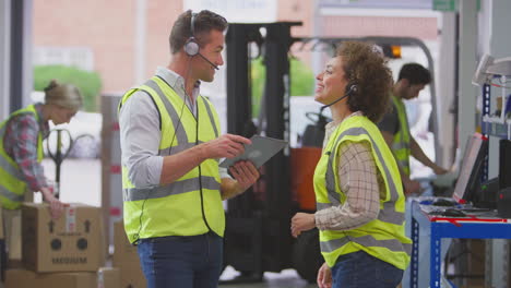 trabajadores masculinos y femeninos que usan auriculares en el almacén de distribución logística utilizando una tableta digital