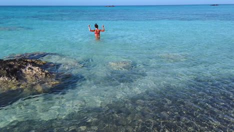 joven entusiasta aprovecha estar sola en las aguas turquesas de la playa de elafonisi para bailar