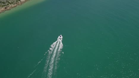 motorboat crossing lagoon navigates deep channel near shore, aerial