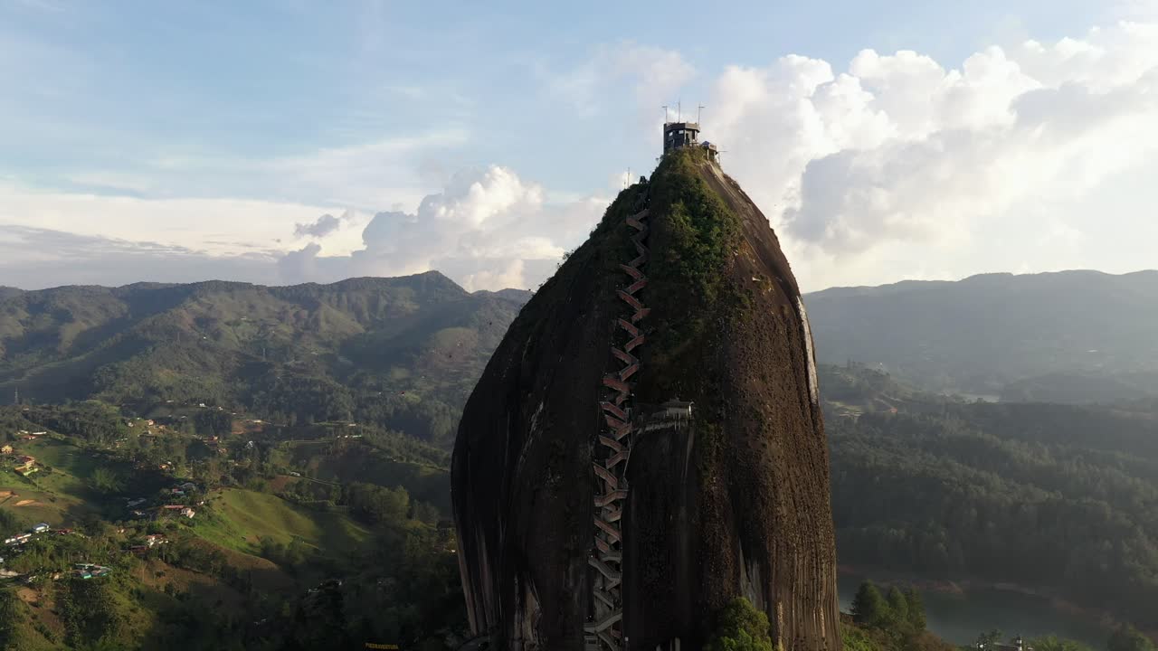 Tomada cinematográfica aérea com afastamento de dolly da Pedra do Peñol durante o pôr do sol na hora dourada em Guatapé, Colômbia