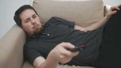 man relaxing on couch with tv remote