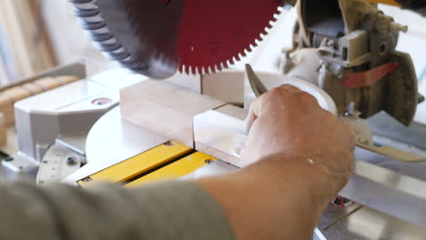 close up shot on a construction worker cutting a piece of angle iron on a metal miter chop saw in a workshop