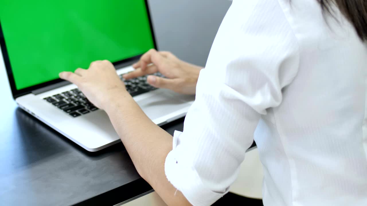 4K : Happy Asian business woman typing on a laptop computer with a key green screen