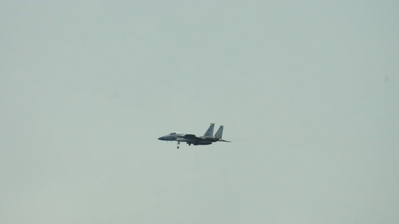 Ett militärt F-15 stridsflygplan flyger genom himlen vid inflygning för landning