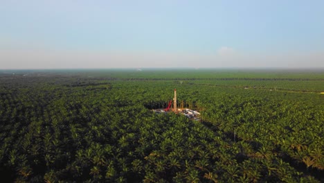 cinematic 4k drone footage of onshore drilling rig equipment structure for oil exploration and exploitation in the middle of jungle surrounded by palm oil trees during sunset and high oil price