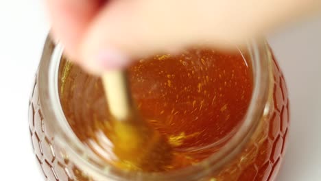 person stirring honey with dipper