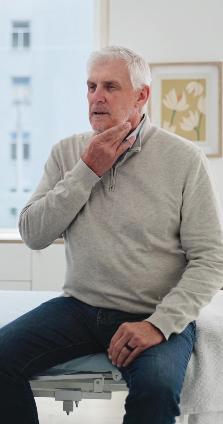 Uomo anziano che si tocca la gola durante una visita medica
