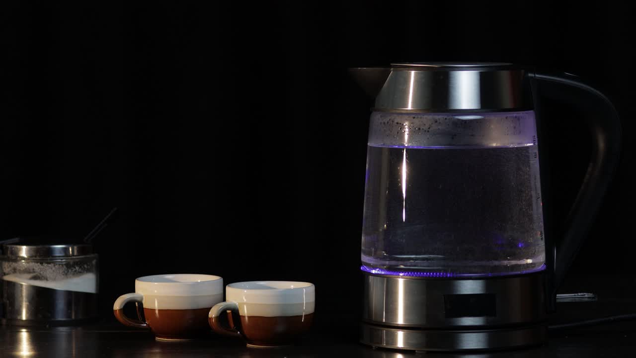 파란 빛 조명과 함께 유리 투명한 전기 ketel에서 는 물. 검은 배경