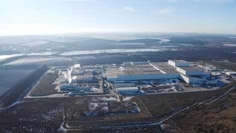 huge industrial plant among nature. view from the air on a modern factory surrounded by fields and forests in winter time. aerial view.