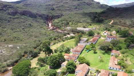 Hileras-De-Viejos-Edificios-Abandonados-Junto-A-Un-Río-Rocoso-En-Colinas-áridas