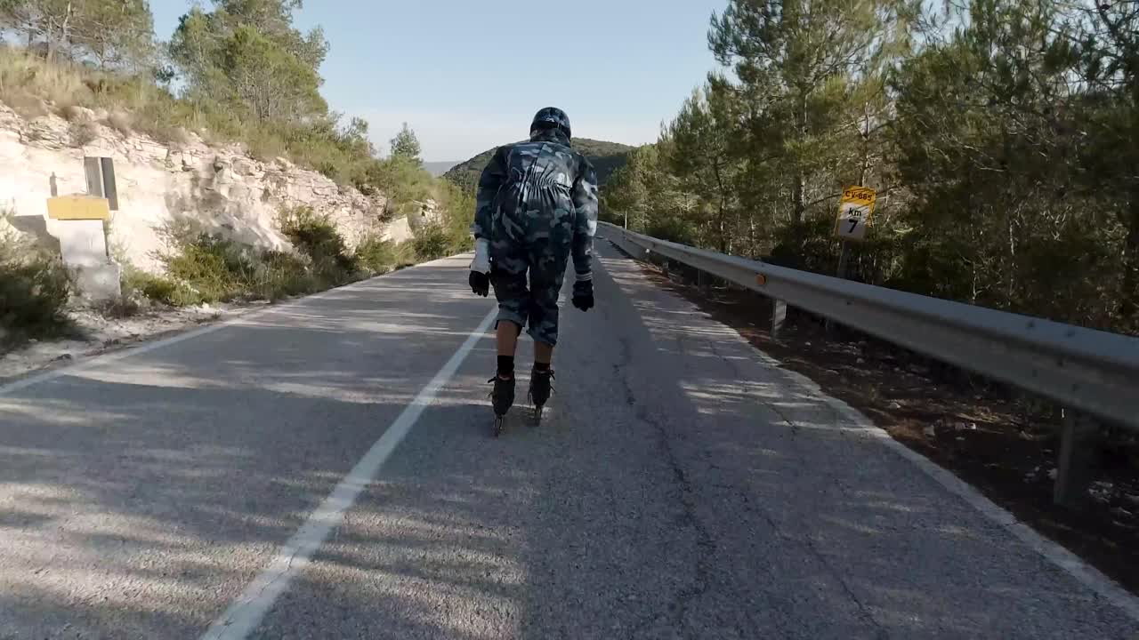 Un pattinatore a rotelle inizia la discesa su una strada di montagna.