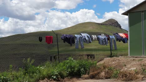 los trabajadores cuelgan la ropa en la valla de la cadena en el sitio de trabajo rural en lesotho