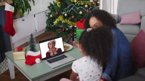 madre y hija afroamericanas felices en videollamada con una amiga en tiempo de navidad
