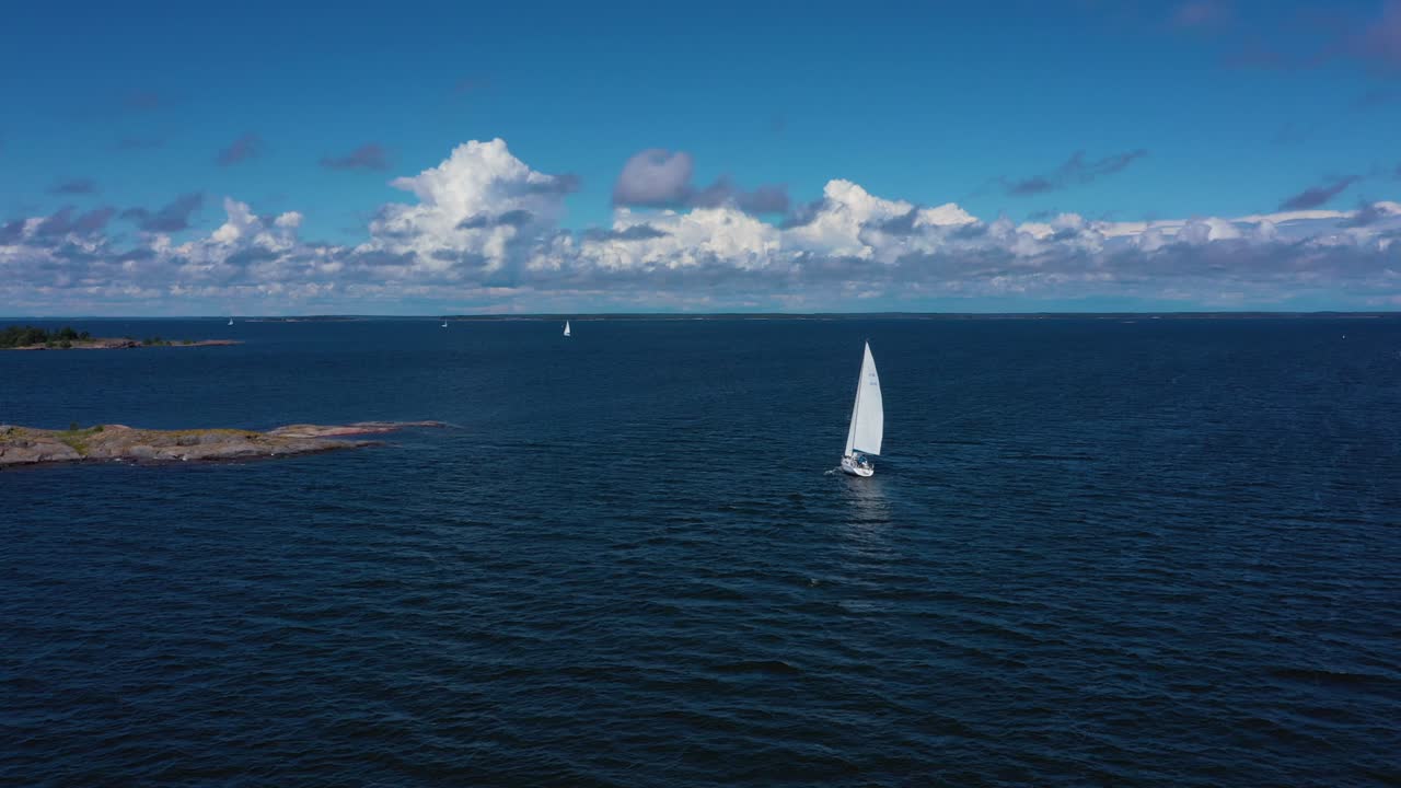 Aerial view overlooking a white sailboat on the high seas, at the Gulf of Bothnia, warm, sunny, summer day, in Stockholm, Sweden - descending, drone shot
