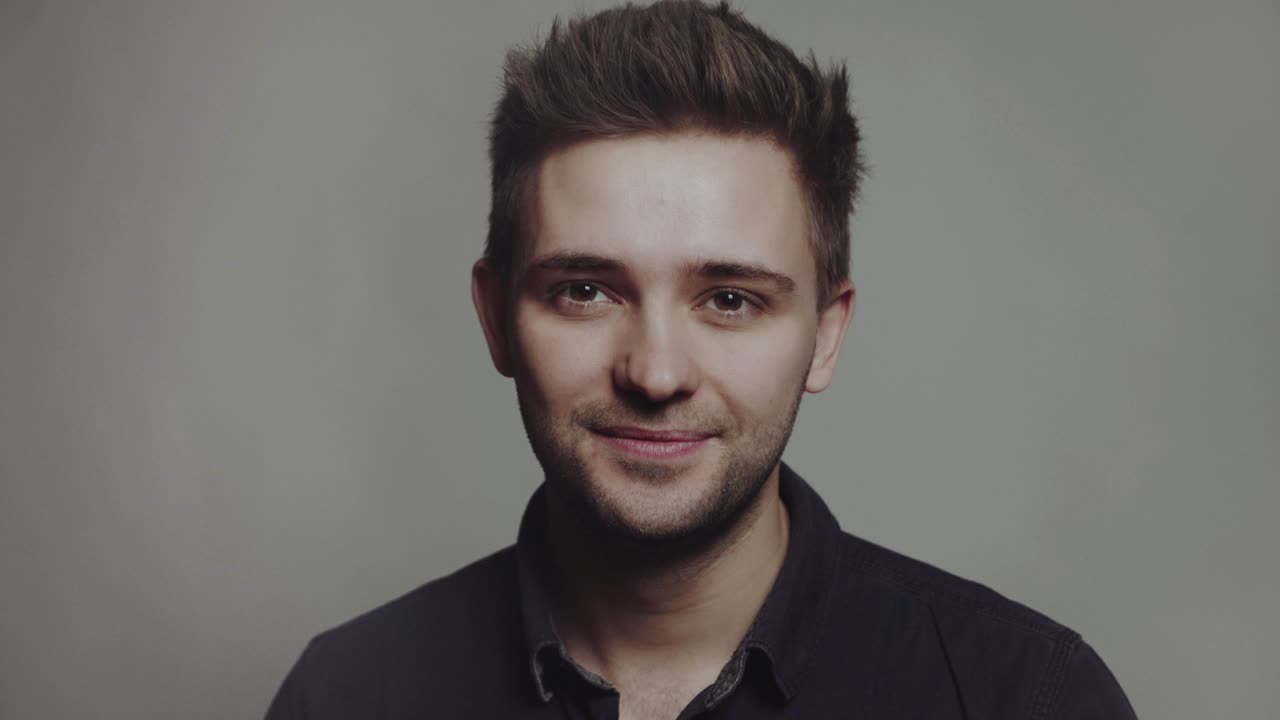 Handsome smiling young man. Portrait of handsome man in a studio on a gray background