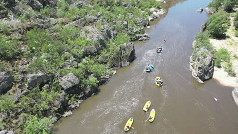 descending aerial tilt: rafters on calm river section in rocky canyon