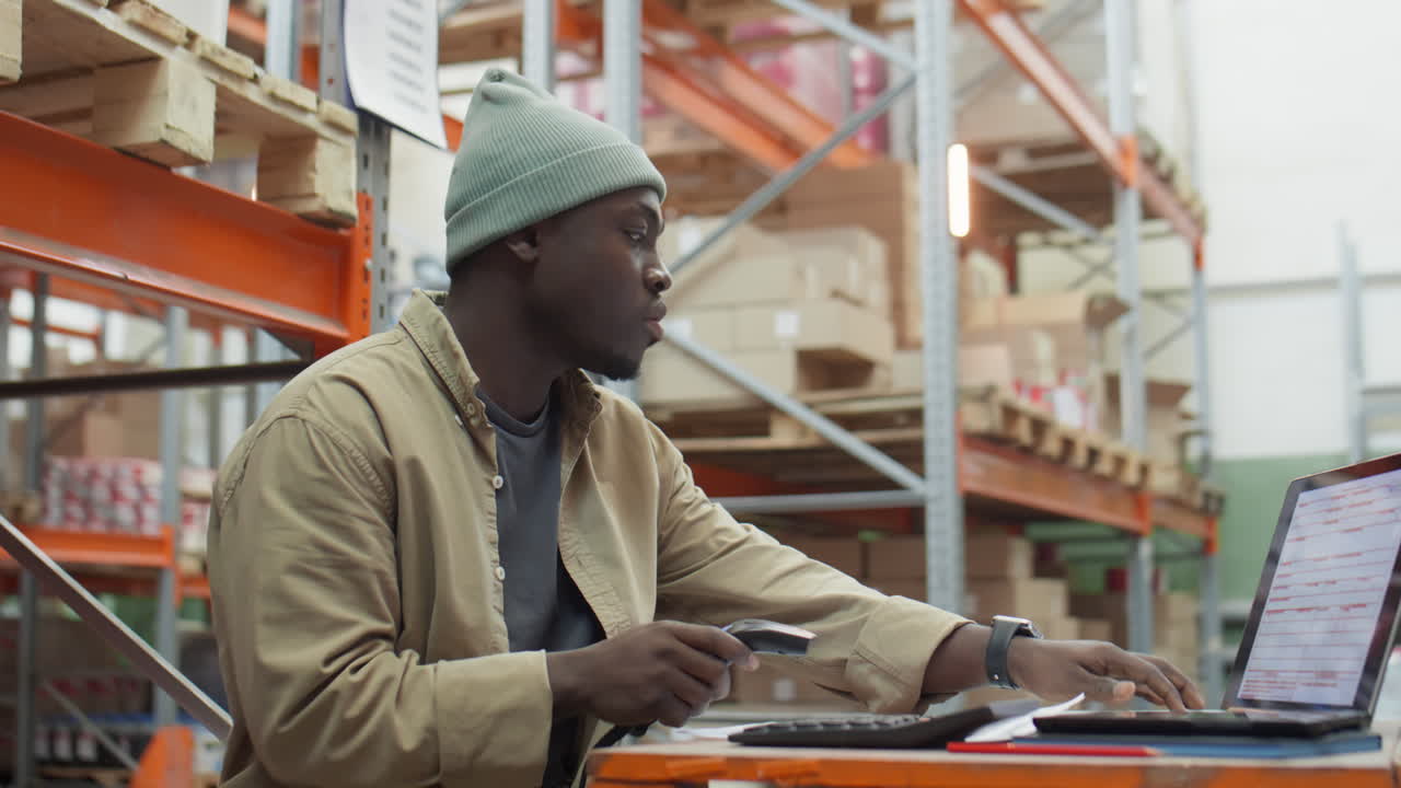 African American Manager Working with Scanner and Laptop in Warehouse