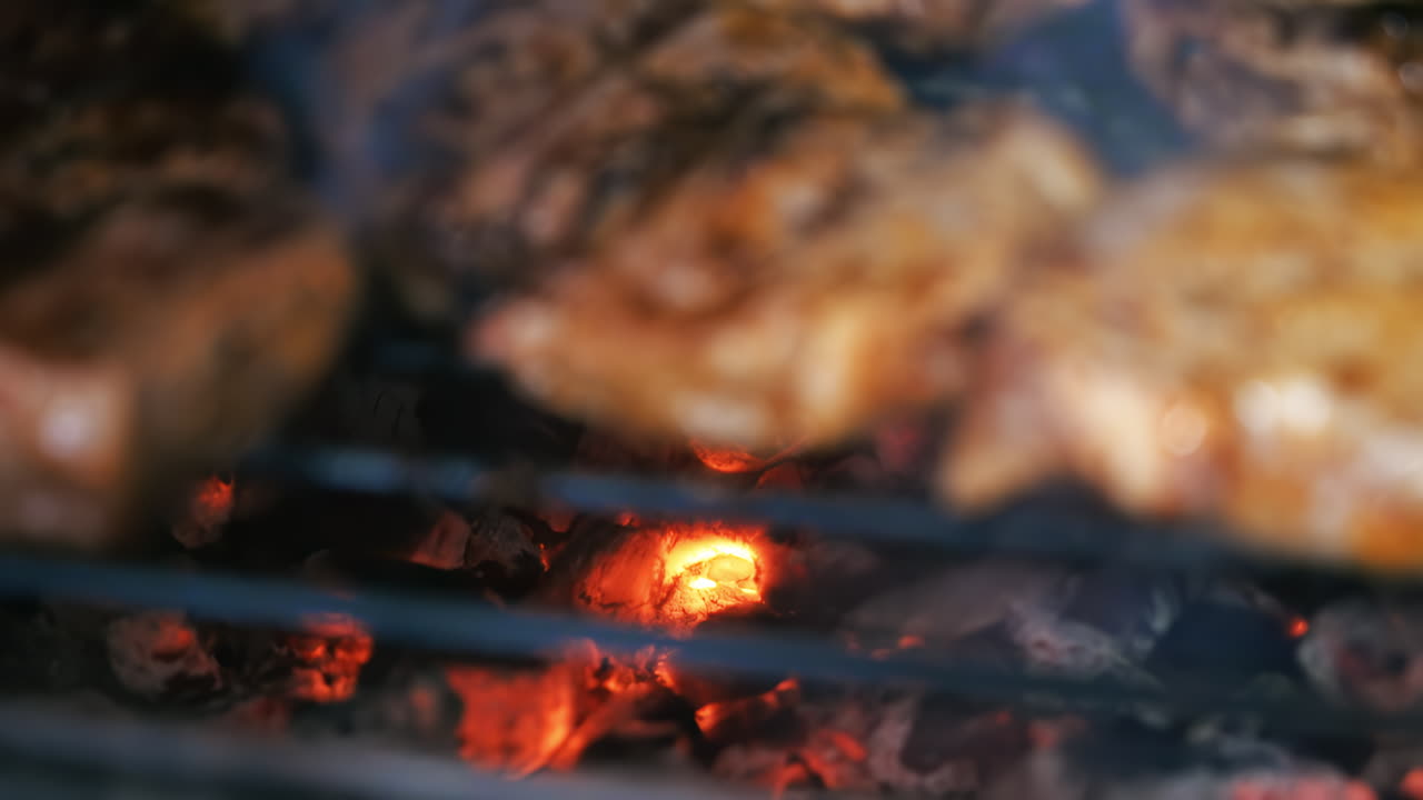 Roasting juicy meat steak with spices and herbs in burning charcoals fire on barbeque grid. Flames and smoke. Close up. Focus transition