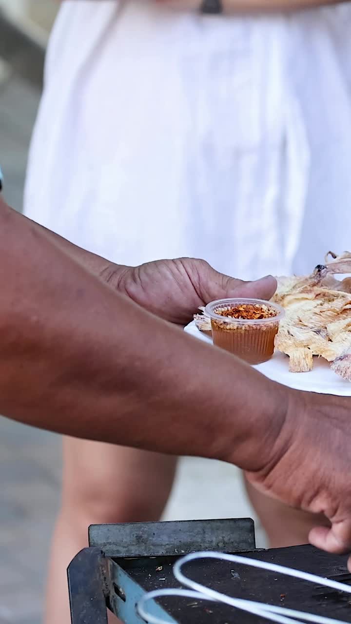 el vendedor sirve calamares a la parrilla a los clientes