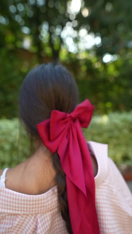 girl with a red bow in a park