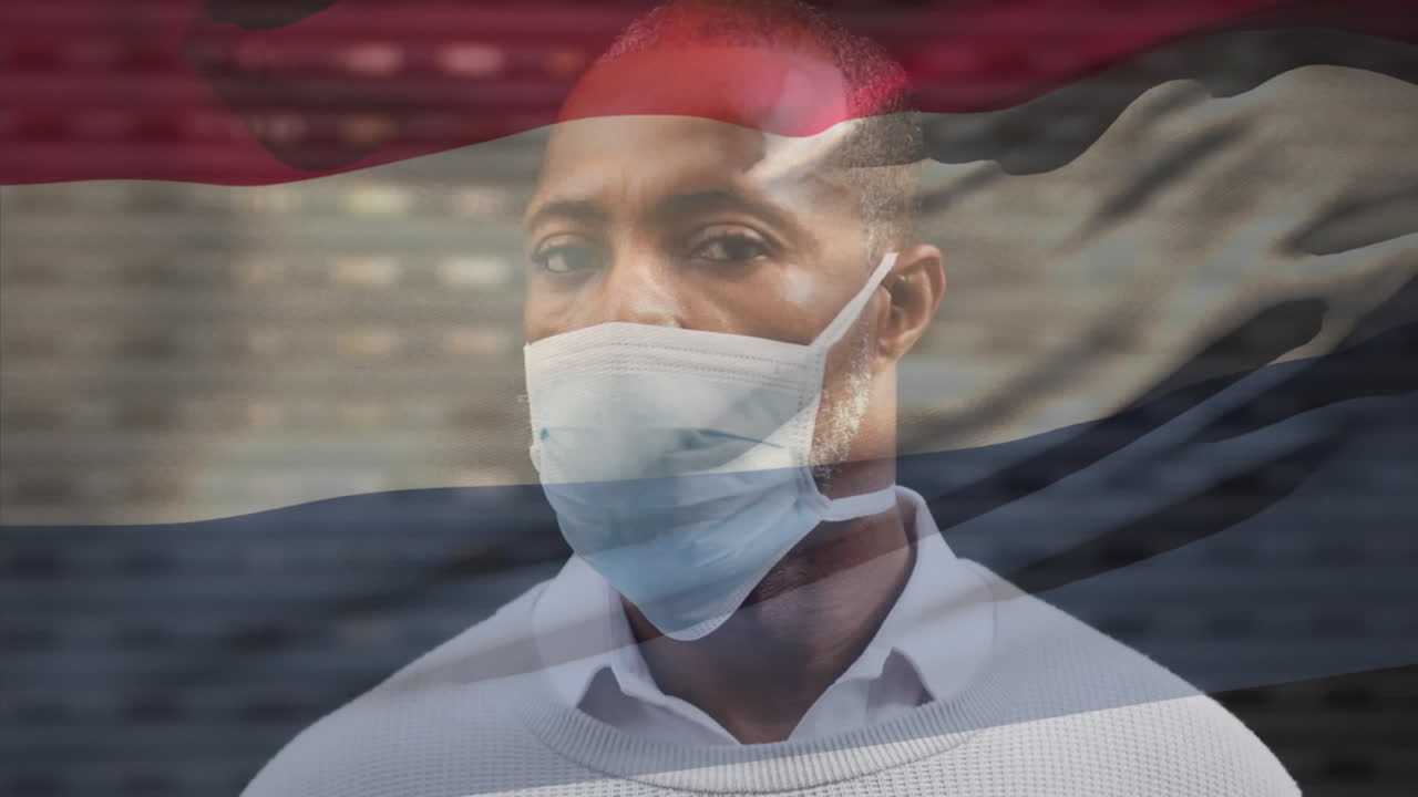 animación de la bandera de los países bajos sobre el retrato de un hombre afroamericano con máscara facial en la calle