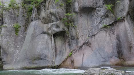 slow motion tilt up over tall stone cliffs next to running river