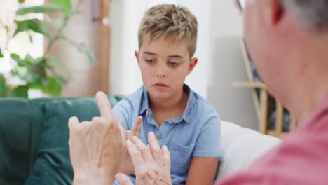 Feliz-Abuelo-Y-Nieto-Caucásicos-Sentados-En-El-Sofá-Y-Usando-Lenguaje-De-Señas,-Cámara-Lenta