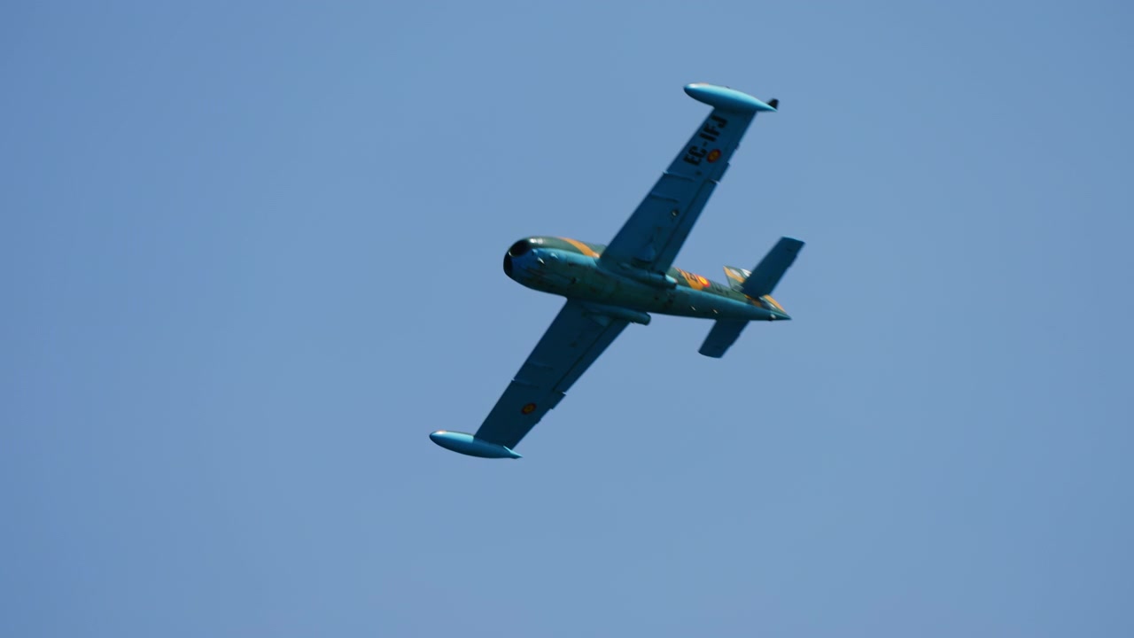 Pesawat jet ringan berbelok tajam di langit cerah.