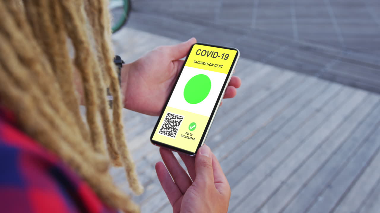 hombre con dreadlocks sosteniendo un teléfono inteligente con certificado de vacunación contra la covid y código qr en la pantalla