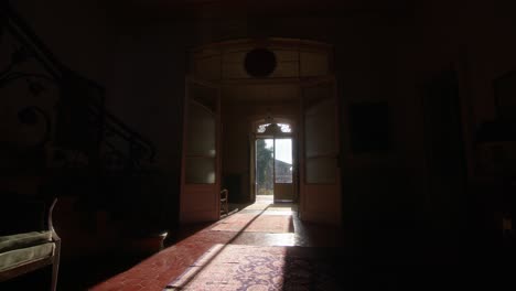 sunlight beams through the entrance of an old italian villa, illuminating the hallway and doors. this static 4k shot captures nostalgia, peace, and mystery in a serene, historic setting.