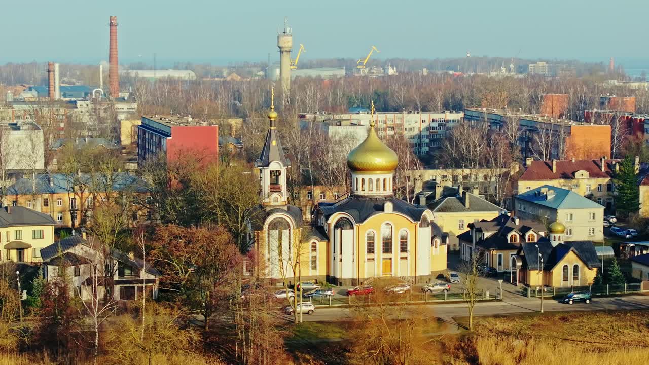 Dronebillede viser ortodoks kirke med gylden kuppel omgivet af efterårsbybillede