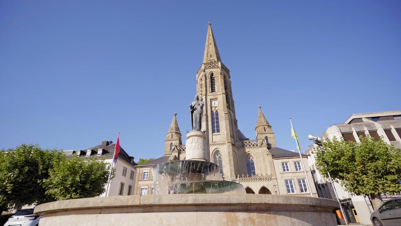 Vidvinkelbillede af Sankt Ludwig Kirke og den historiske fontæne med en religiøs statue i centrum af Saarlouis, Tyskland
